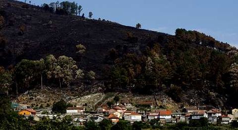 El fuego cerc� las viviendas durante horas e hizo saltar el p�nico entre los habitantes de esta zona de O Rosal. La imagen muestra todo el monte calcinado sobre las casas.