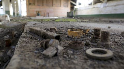 Tornillos y tuercas abandonados y cubiertos de polvo en el interior de la empresa