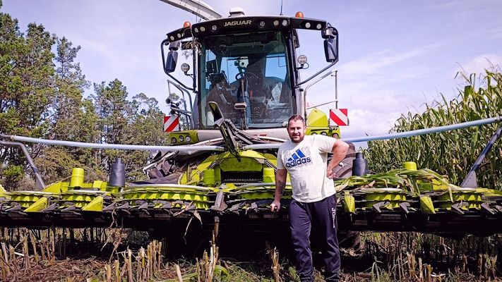 Jonathan Rodríguez, al pie de su cosechadora Claas 990, en un cultivo de maíz en Mazaricos.