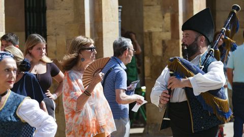  Una turista se abanica ante un gaitero en la Plaza de Ayuntamiento de Oviedo