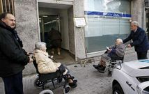 Jos� Luis Iravedra (izquierda), empujando la silla de ruedas de una mujer para llevarla a votar. 