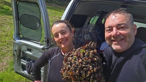Rosario y Marcos, una pareja de percebeiros, exhiben orgullosos su bot�n de percebes nada m�s terminar la jornada laboral.
