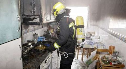 Uno de los bomberos trabajando en el interior de la cocina donde se produjo el incendio.