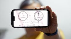 Un hombre sostiene un tel�fono m�vil con un gr�fico sobre el cambio de hora en la pantalla.