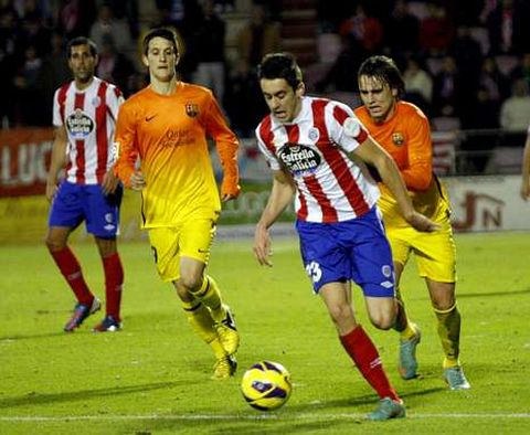 El canterano rojiblanco Iago D�az, con el bal�n entre dos jugadores del Barcelona B.