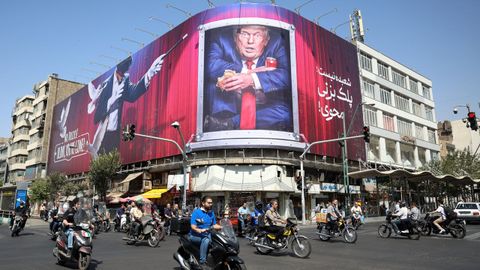 Un grupo de motoristas circulan por las proximidades de una lona contra Donald Trump, el presidente de Estados Unidos, en la capital del pa&iacute;s, Teher&aacute;n.