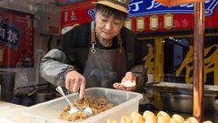 Una mujer prepara empanadillas en una concurrida calle turstica de Pekn (China)
