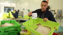 Manuel Tom�s Abal, subastador en la lonja de Ribeira, muestra una etiqueta del sello de calidad