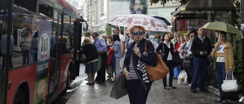 Un grupo de ciudadanos espera en la parada de la plaza de Orense a la llegada del autobús.