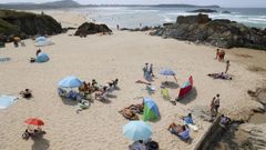 Baistas se protegen del nordeste en la playa A Frouxeira,en Valdovio, el sbado