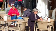 Varias personas sentadas y tomando caf� en una terraza de Oporto.
