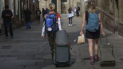 Dos turistas caminan por el casco histrico de Santiago con sus maletas