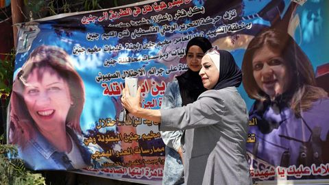La periodista palestina Shatha Hanaysha (2d), quien vio desplomarse a su lado a la periodista de Al Yazira Shireen Abu Akleh por un disparo en la cara, mientras les llov�an las balas, posa junto a un cartel en memoria de la periodista de Al Yazira Shireen Abu Akleh, en Yen�n,