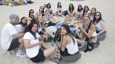 Un grupo de jvenes, vestidos de marineros y marineras, disfrutan de la comida en la playa en la pasada edicin de A Maruxaina.