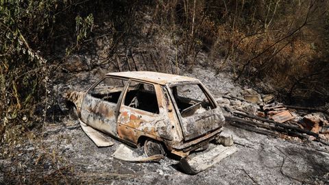 Un coche calcinado durante el incendio en el entorno de A Abelleira, en As Neves.