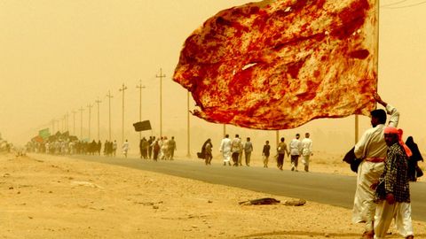 Un chi� iraqu� porta una bandera manchada con la sangre de hombres que se hirieron para demostrar su amor al Imam.