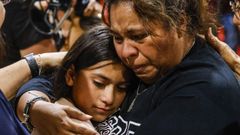 Una mujer llora mientras abraza a una ni�a, en una vigilia en el condado de Uvalde.