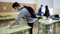Un alumno desinfecta su mesa y silla en el IES Ollos Grandes de Lugo en el regreso a las aulas 