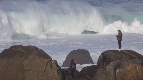 Varias personas observan el temporal en la costa de Mux�a.