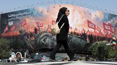 Una mujer pasea frente a un mural con propaganda proiran� y antiamericana.