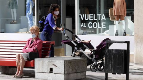  Una mujer camina frente a un escaparate con la campaa de la vuelta al colegio en una calle del centro de Oviedo