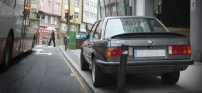 Un coche aparcado con las cuatro ruedas sobre la acera en el tramo inicial de la ronda de Outeiro. 