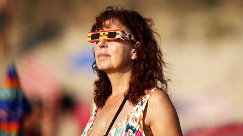 Una mujer mira al eclipse en la playa de Doni�os.