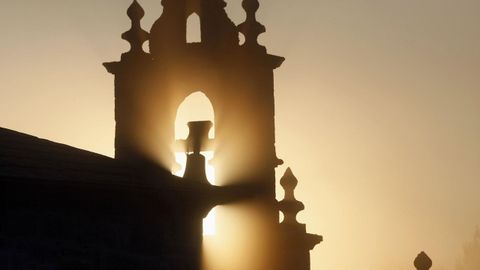 Puesta de sol entre la niebla en la iglesia de San Miguel de Orbazai, en Lugo