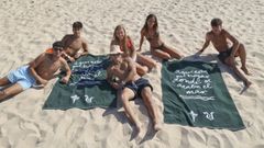 Un grupo de j�venes aficionados con las toallas del Racing en un d�a de playa. 