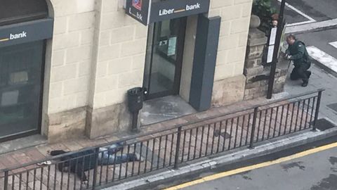 Uno de los atracadores de Cangas de Ons boca abajo en la acera delante de la oficina de Liberbank.Uno de los atracadores de Cangas de Ons boca abajo en la acera delante de la oficina de Liberbank