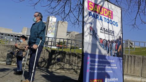 Un paciente reci�n operado de cadera posa delante del hospital de Matosinhos al lado de un cartel de Iniciativa Liberal