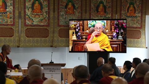 Monjes budistas siguen el mensaje en vídeo del dalái lama.