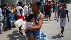 Una mujer cargando con su beb� se dispone a hacer cola para aprovisionarse de agua en Caracas