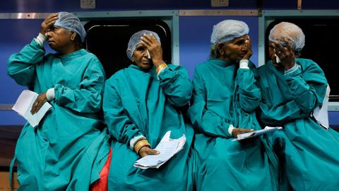 Un grupo de pacientes se cubren los ojos antes de someterse a una operación de cataratas en un hospital construido dentro de un tren, en la India