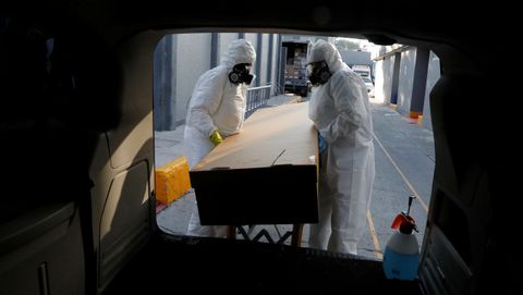 Trabajadores de una funeraria de Ciudad de México transportan el féretro de un fallecido por covid-19
