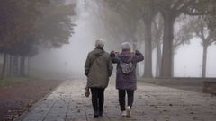 Dos personas mayores pasean entre la niebla en O Burgo (Culleredo)