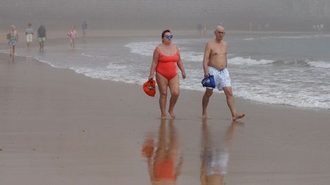 Un grupo de personas pasea por la Playa de San Lorenzo en Gij�n que este mi�rcoles amaneci� cubierta de bruma durante la fase 2 de la desescalada del confinamiento por la pandemia de Covid-19