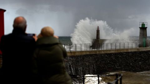 Un grupo de personas toma fotos del mar estrell�ndose contra el puerto de Viavelez.