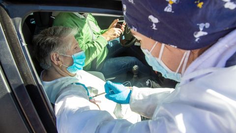 En algunos lugares, se establecieron puntos de vacunación sin bajar del vehículo. En la imagen, una sanitaria inyecta la vacuna a una vecina de Badajoz