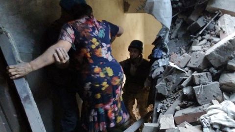 Personal de emergencia ayuda a una mujer a salir de un edificio convertido en escombros en la localidad de Toretsk, en la provincia de Donetsk