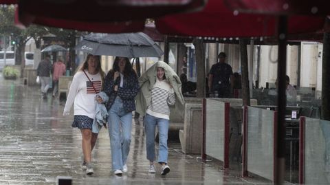 Tres amigas intentan protegerse de la lluvia entre las terrazas de las cafeteras de la calle Cardenal de Monforte este martes, el ltimo da de las fiestas