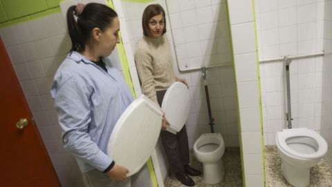 Nuria Otero y Vanessa Higuera, con las tapas de protesta y ante los ba�os sin puertas.
