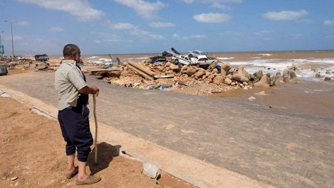 Un hombre mira los coches arrollados por la tormenta y amontonados en la costa deDerna, Libia