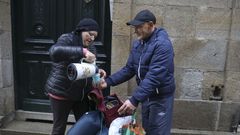 En medio de la calle, ofreciendo un chocolate caliente a una de las personas a las que ayuda normalmente