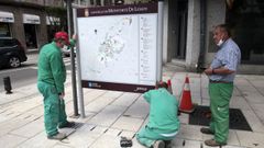 Trabajadores municipales reparando un panel de informaci�n tur�stica en la calle Cardenal, en imagen de archivo