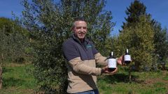 Gonzalo Garc�a posa en su olivar con botellas de la primera producci�n de Olea Atl�ntica.