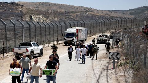 Población drusa camina con sus pertenencias en el paso de los Altos del Golán en dirección a Siria