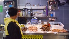 Una mujer observa el puesto de mariscos de la plaza de Lugo que Mery atendi durante dcadas y en el que se expone un artculo del peridico sobre la vendedora