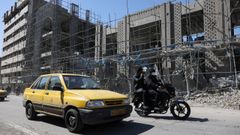 Un coche pasa ante un edificio afectado por bombardeos en Teher�n