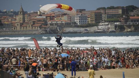 La playa de San Lorenzo repleta de gente durante el aterrizaje de un paracaidista.